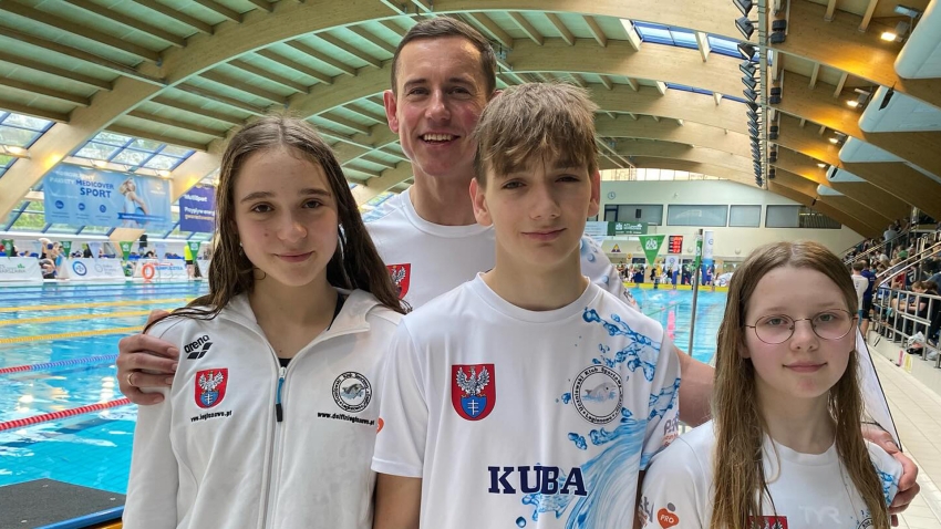Trójka dzieci, zawodników w pływaniu i trener