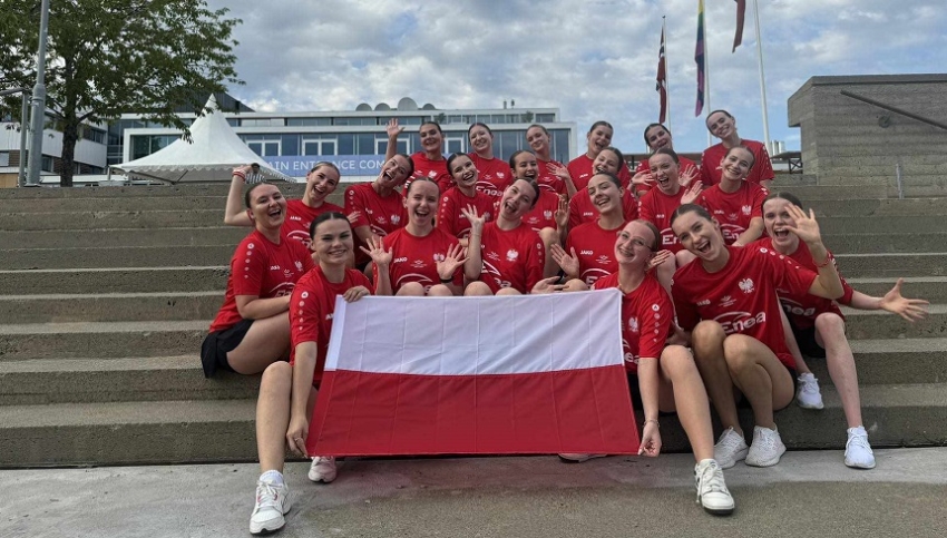 Zawodniczki siedzą na schodach, cieszą się, trzymają w ręce flagę Polski