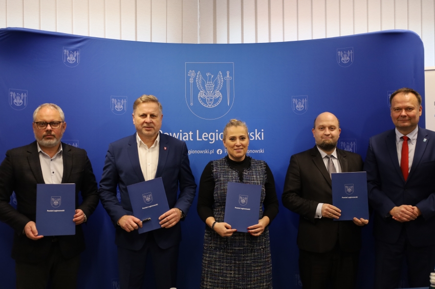 Pięć osób trzymających teczki z herbem powiatu legionowskiego