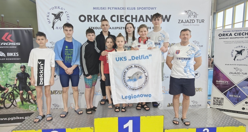 zawodnicy pozują z klubową flagą stojąc na podium