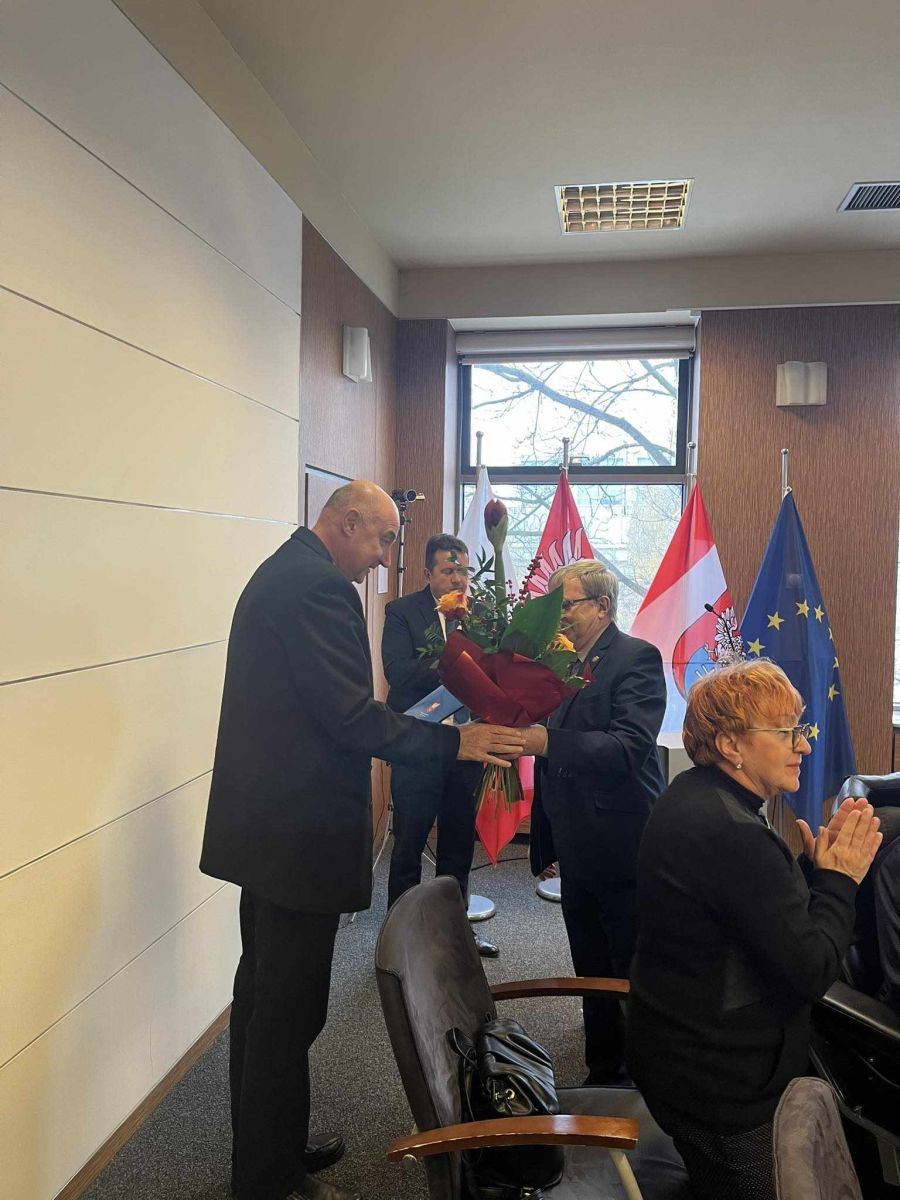 wręczanie kwiatów księdzu, w tle Prezydent Miasta Legionowo